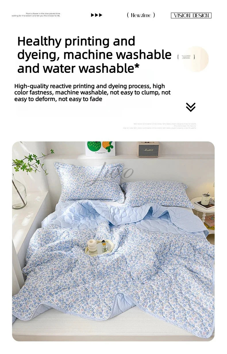 A light blue floral quilt set is displayed on a bed, featuring a delicate pattern.