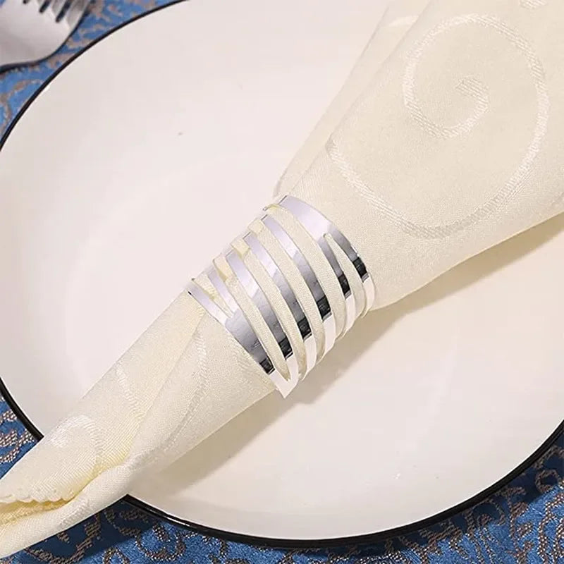 Elegant silver metal napkin rings placed on a white plate with a blue patterned cloth background.