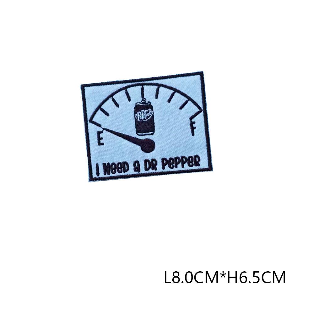 A black embroidered letter patch featuring a thermometer design and the text I NEED A DR PEPPER