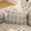 A close-up of a fluffy gray faux fur throw pillow cover resting on a light-colored surface.
