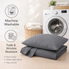 A stack of gray microfiber pillow covers and a washing machine are shown on a wooden surface.
