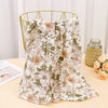 A beige floral patterned cloth fabric draped over a gold wire hanger.