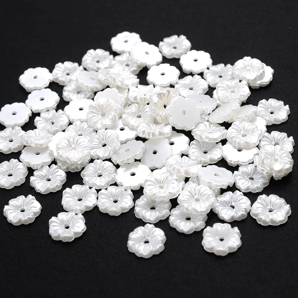 A pile of small, white imitation pearl flower spacer beads for DIY jewelry.