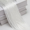 A long, sheer white thread curtain tie-back is draped over a stack of white boxes.