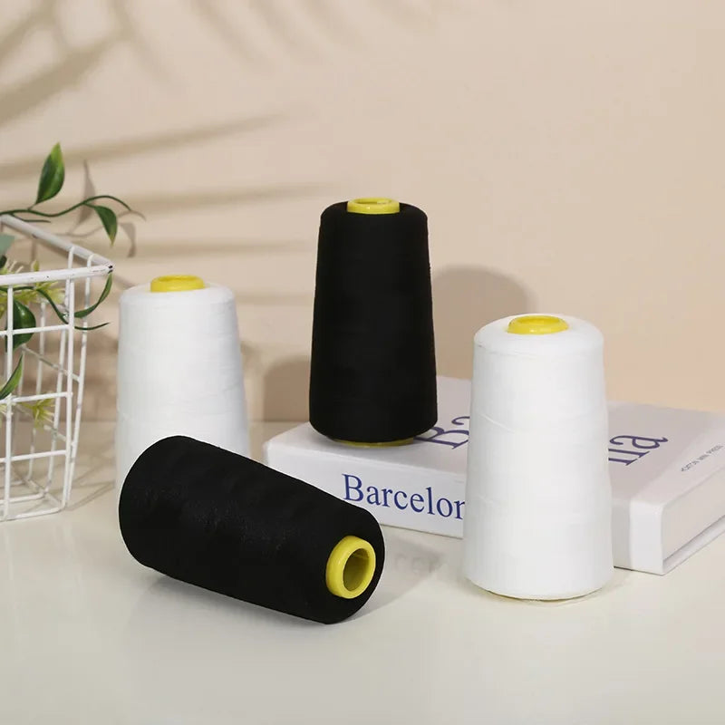 Rolls of black and white polyester sewing thread with yellow cores displayed on a white surface.
