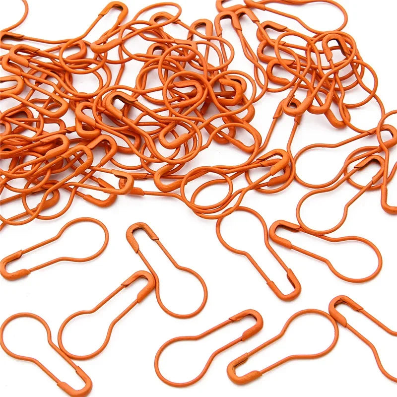 A pile of orange safety bulb pins for knitting and sewing.