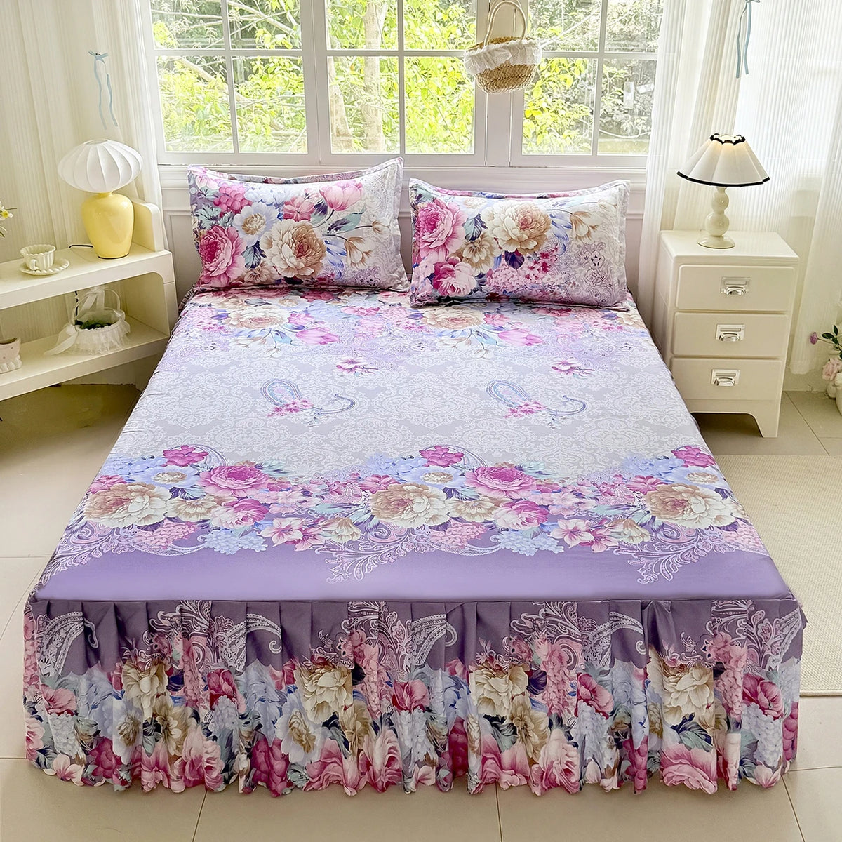 A purple and pink floral print bed skirt set featuring roses and greenery on a bed.