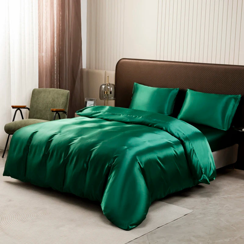 A luxurious emerald green satin bedding set displayed on a bed with brown upholstery and sheer curtains.