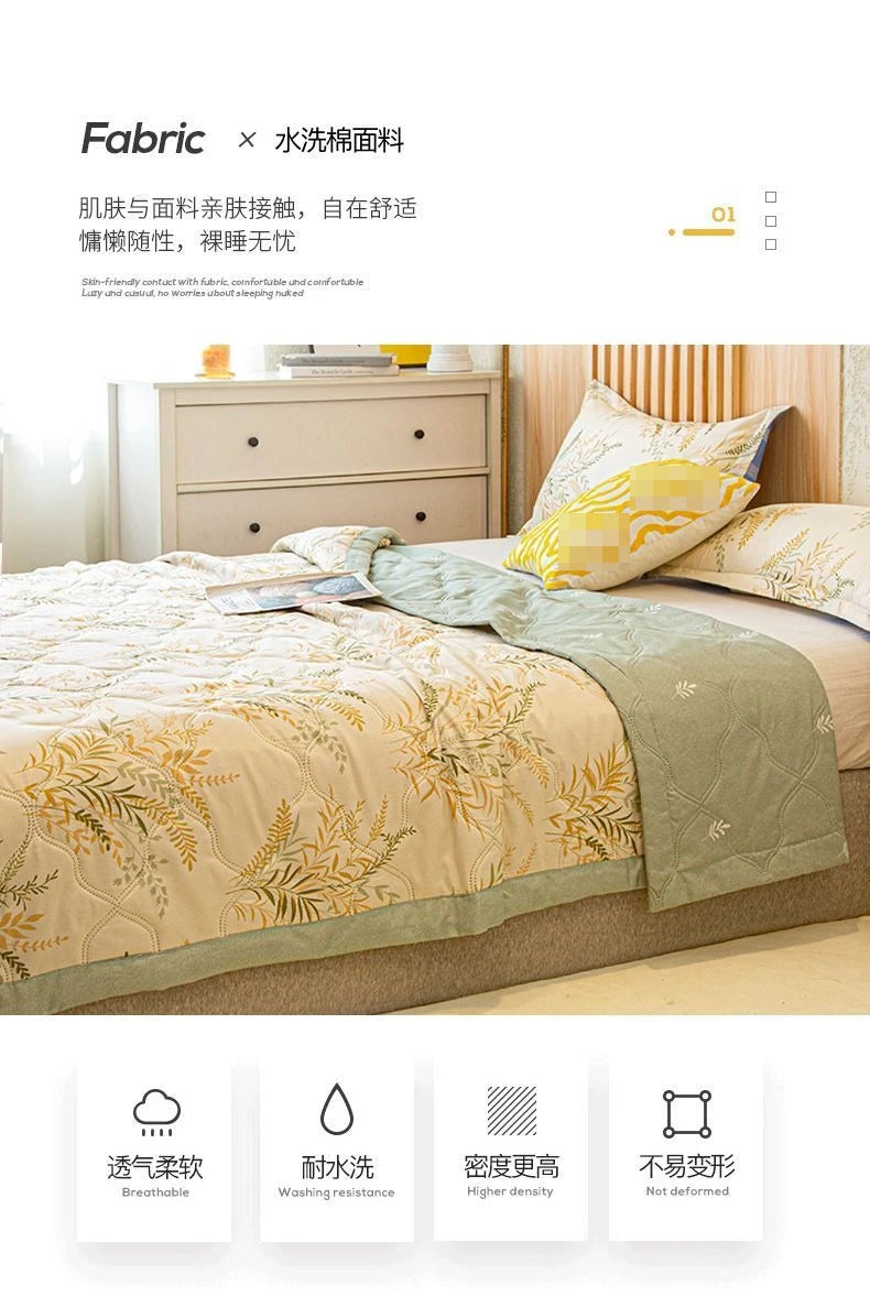 A beige quilted bedspread with gold floral embroidery is displayed on a bed, next to a wooden dresser.