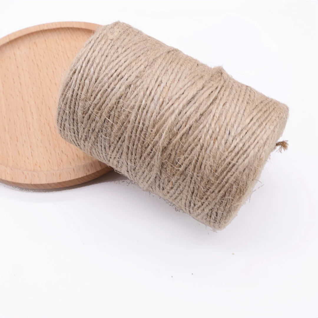 A roll of natural jute twine used for crafts and decor, lying next to a light wooden board.