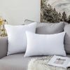 A white throw pillow insert with bounce-back support resting on a gray sofa.
