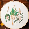 Floral cross stitch embroidery kit featuring a potted plant with green leaves and a wreath of small green berries