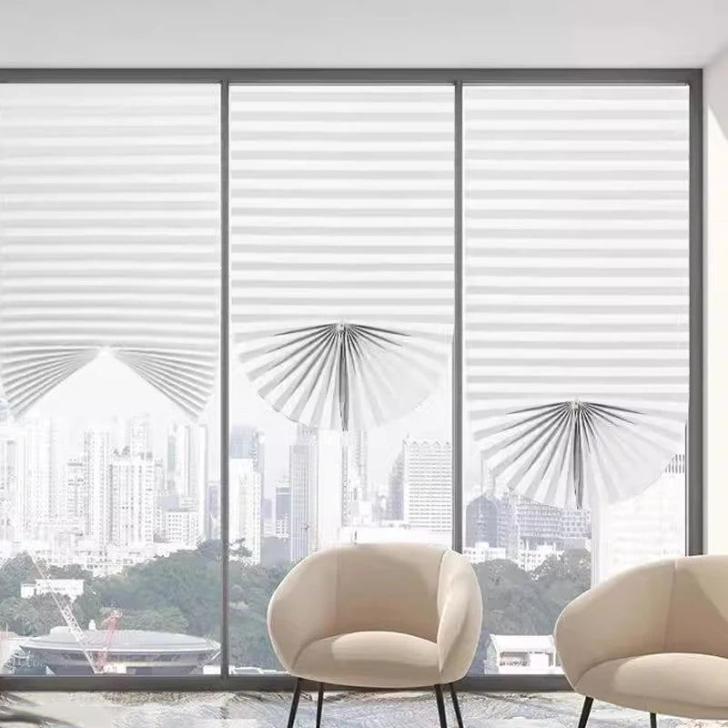 A view through large glass panels showing a city skyline and a light-colored armchair.