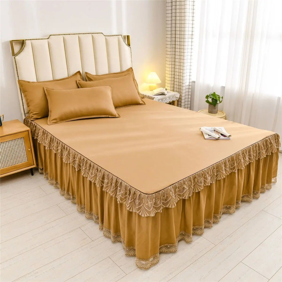 A luxurious gold floral bed skirt protecting a mattress, displayed on a bed with a upholstered headboard.