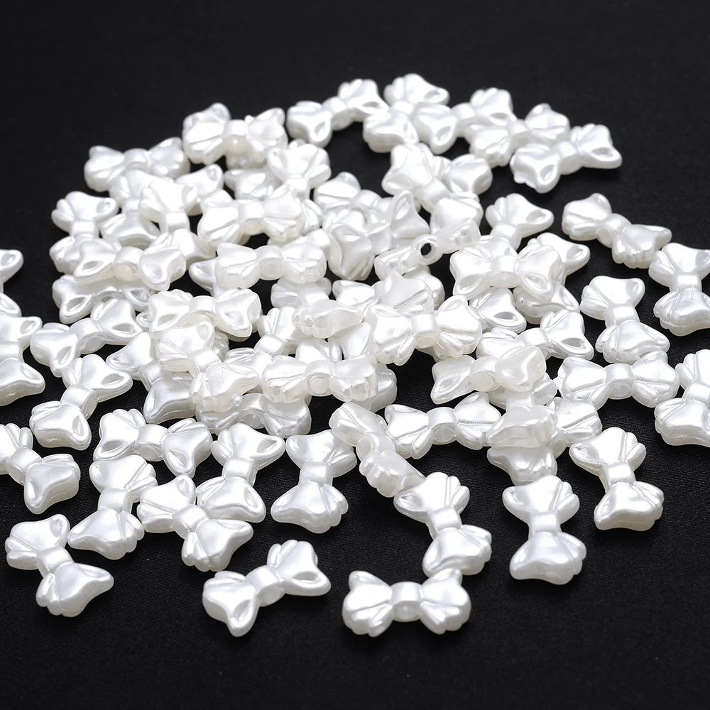 A pile of small, white imitation pearl flower spacer beads for DIY jewelry.