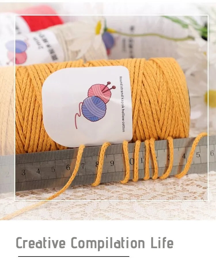 A ball of yellow-orange hand-woven cotton yarn is displayed next to a ruler, showing the thread for crafting.