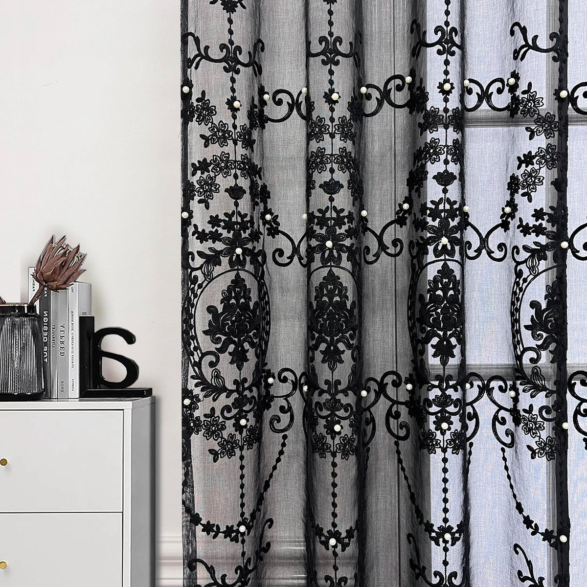 Black sheer curtain featuring intricate lace embroidery with pearl accents.