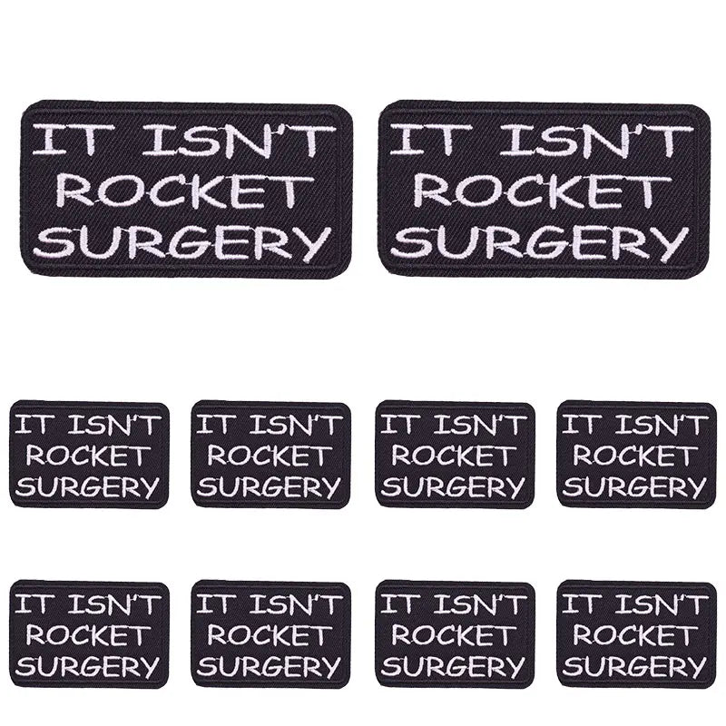 Two black embroidered patches with the text IT ISN'T ROCKET SURGERY