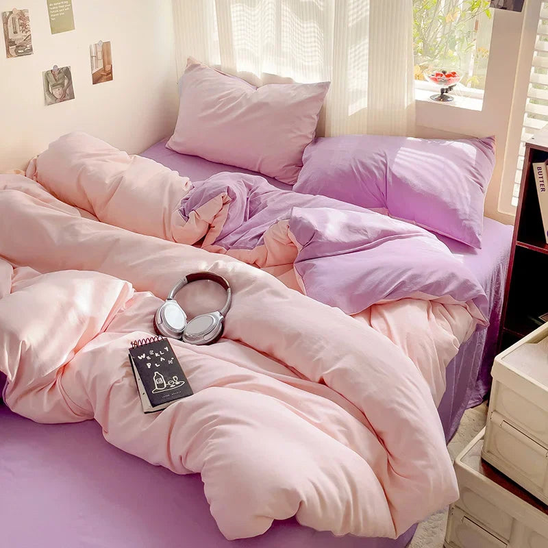 A pink and purple cotton bed linen set featuring pillows and a duvet on a bed.
