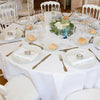 Elegant white satin round tablecloths set for a formal dining event with silverware and glassware