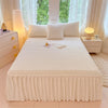 A white plush bed skirt linen set displayed on a bed with white pillows and natural light.