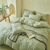 A light green luxury Nordic quilt duvet set displayed on a bed with pillows and a striped throw.