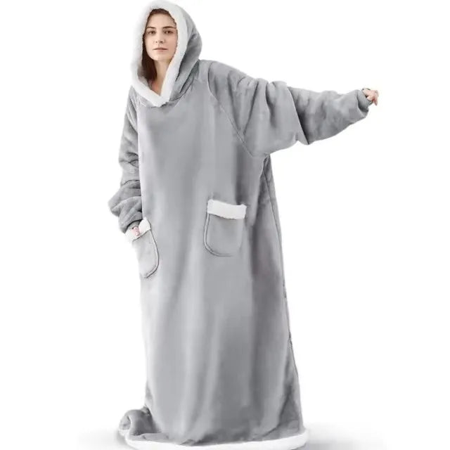 A person wearing a oversized gray flannel blanket pyjama set with a hood.