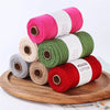 A stack of hand-knitted cotton yarn in various shades of pink, green, and red on a wooden board.