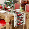 Christmas pine cone and red berry linen table runner on a wooden dining table.