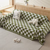 A green and white checkerboard sofa slipcover draped on a light rug.