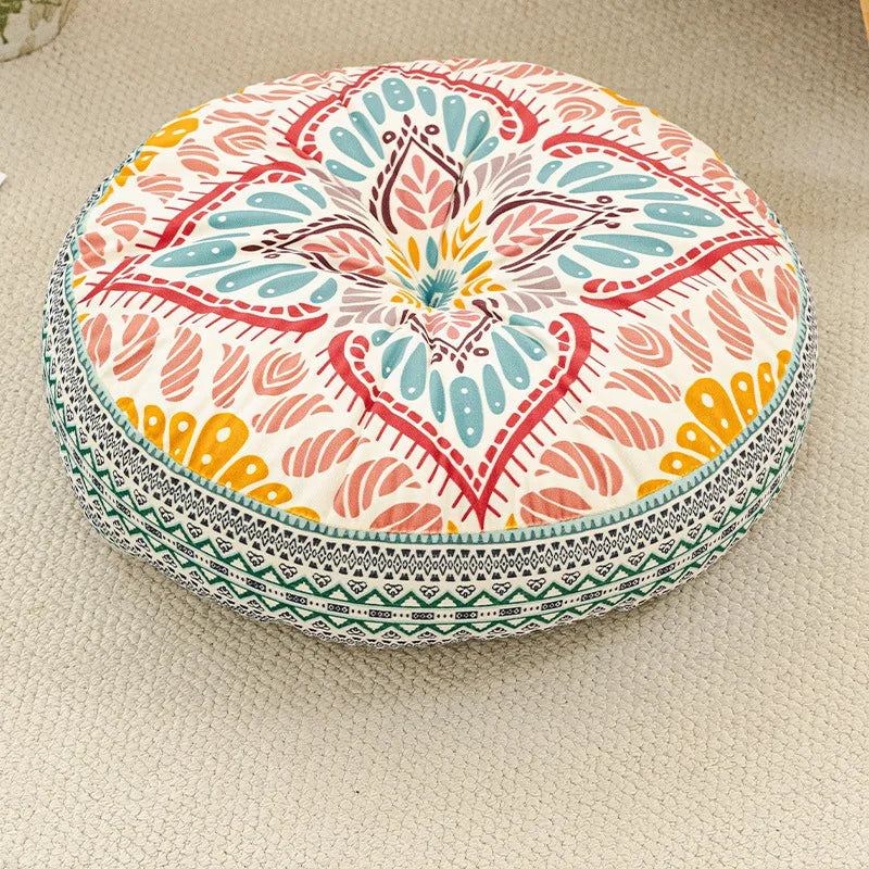 A round bohemian tatami cushion featuring intricate floral patterns in pink, teal, and orange on a light background.
