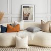 A collection of cream and beige textured boucle throw pillows arranged on a light-colored sofa.