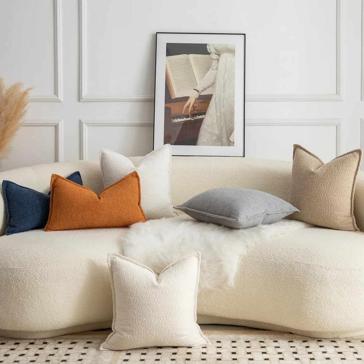 A collection of cream and beige textured boucle throw pillows arranged on a light-colored sofa.