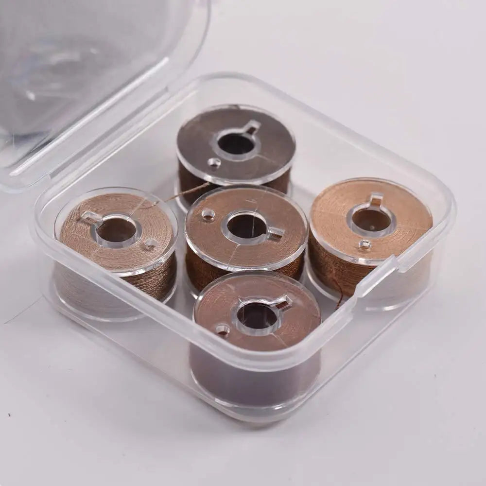 A clear plastic container holds several spools of prewound sewing machine bobbin threads.