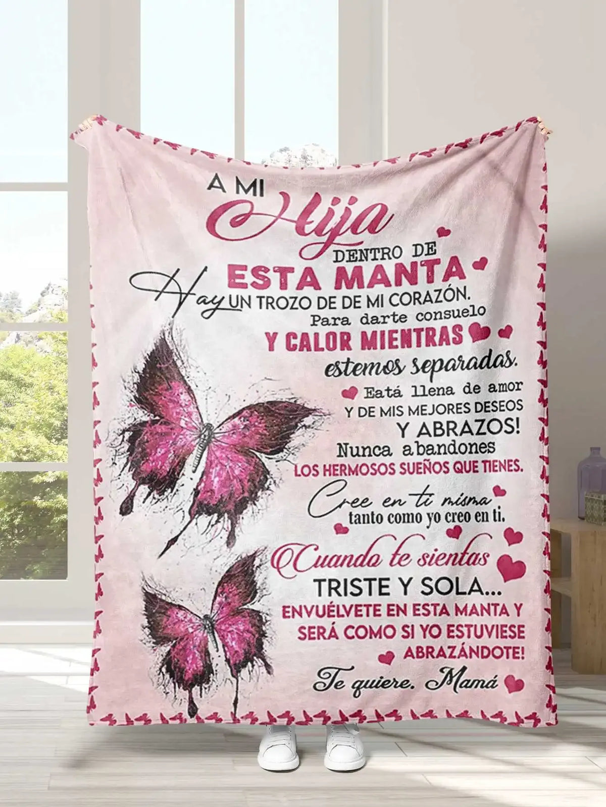 A pink embroidered blanket featuring Spanish text about love and comfort with butterfly designs