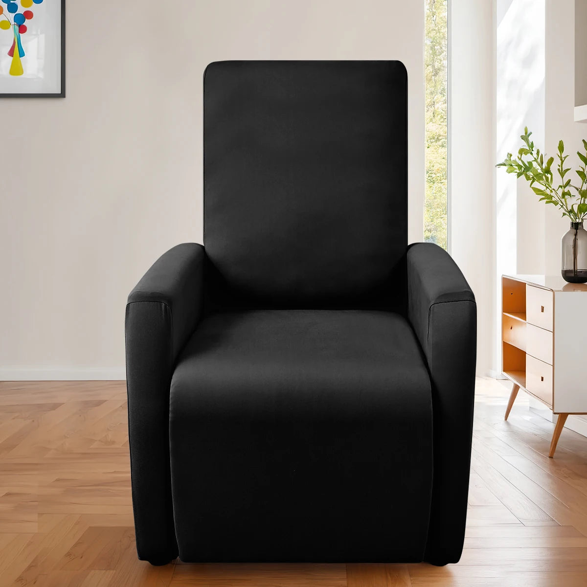 A modern black accent chair with a padded seat and armrests is shown in a bright room.