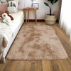 A plush solid black area rug with long fibers placed on a wooden floor next to a bed.