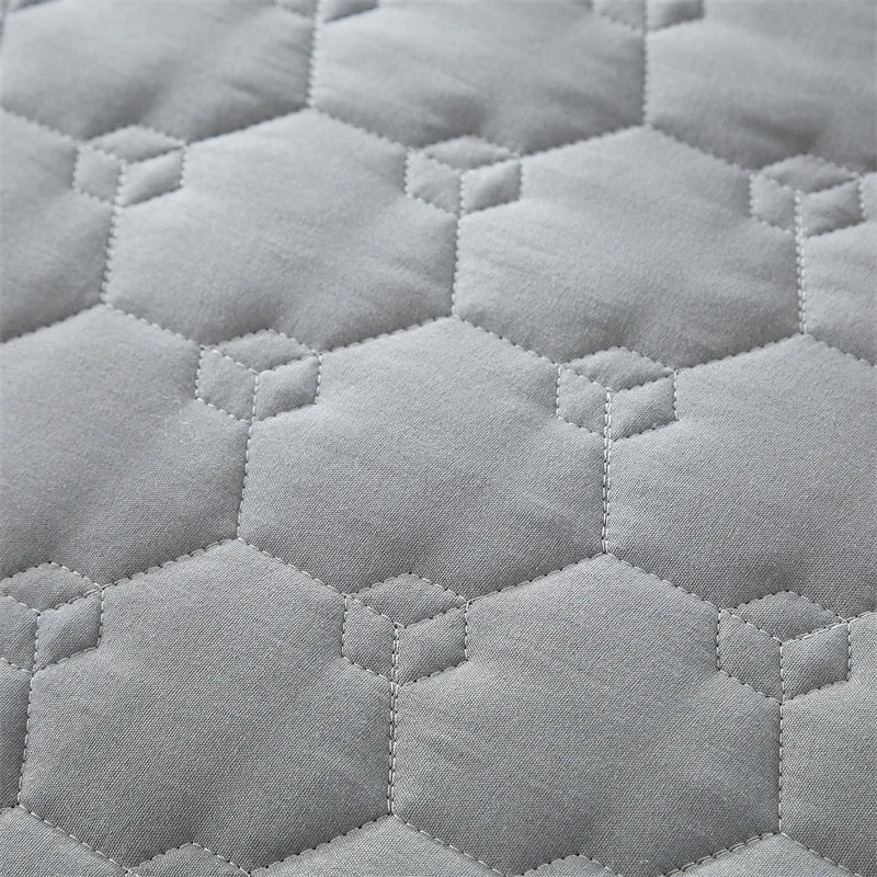 Light gray quilted fabric texture showing a repeating hexagonal pattern.