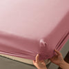 A close-up of a pink soft touch microfiber fitted sheet being held up to show its deep pockets.