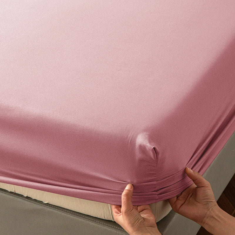 A close-up of a pink soft touch microfiber fitted sheet being held up to show its deep pockets.