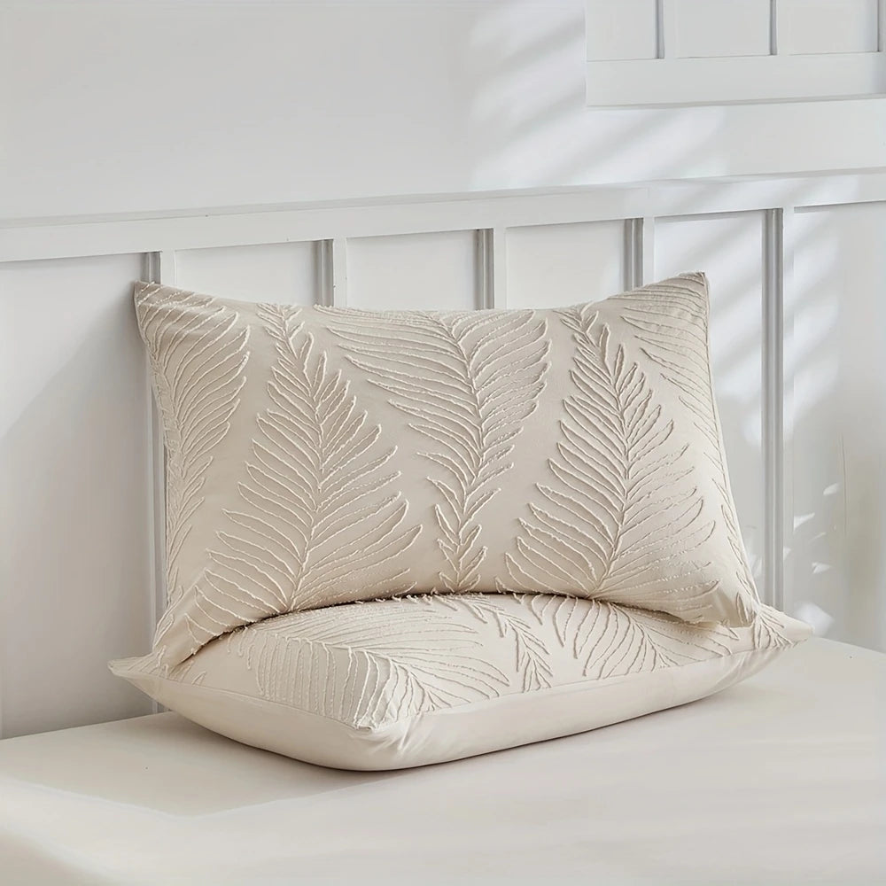 A cream embossed leaf duvet cover set resting on a white surface.