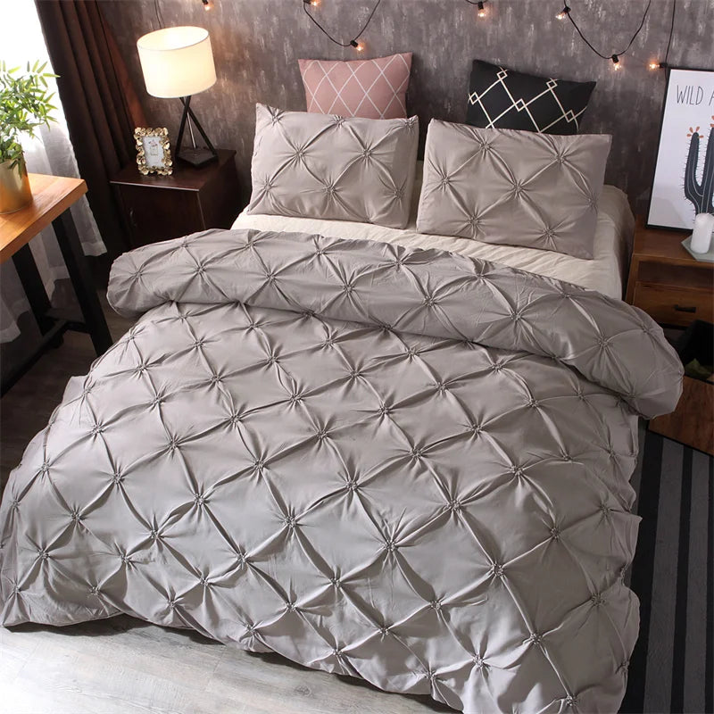 A queen comfort set featuring gray quilted bedding and pillows on a bed.