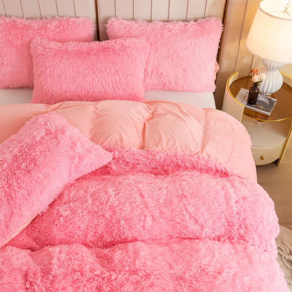 A set of pink fluffy pillows and a pink plush duvet cover on a bed.