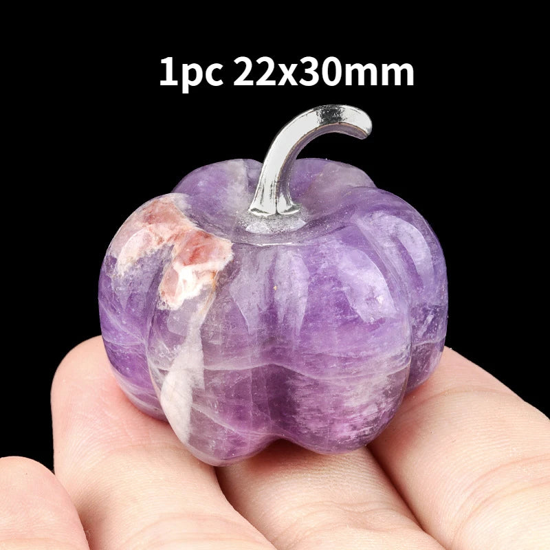 A purple natural stone pumpkin figurine with a silver stem is held in a hand.