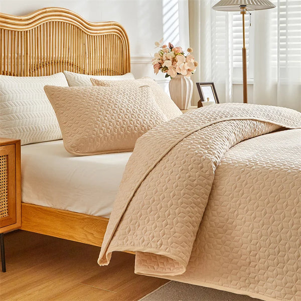 A beige plaid quilt set is displayed on a queen bed with light wood accents and white bedding.