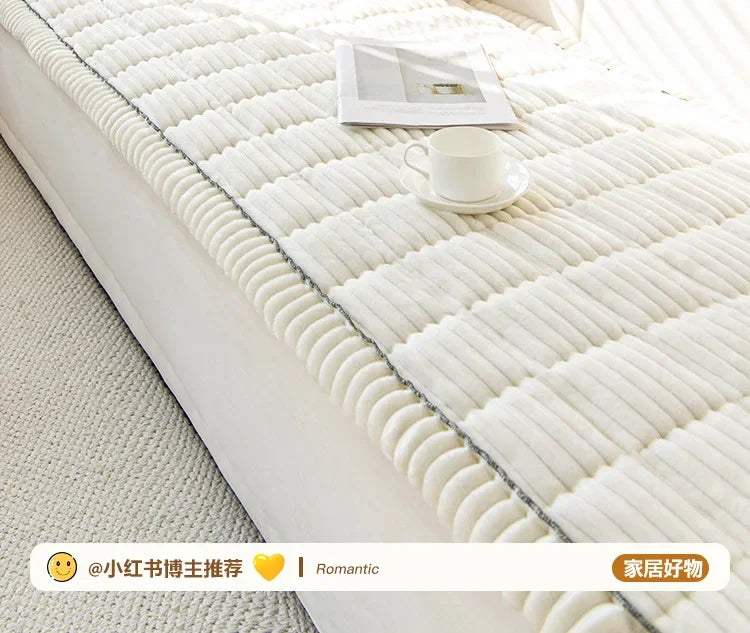 A white quilted sofa armrest cover with ridged edges and a cup of coffee resting on the fabric.