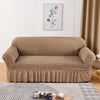 A beige stretch knit sofa cover featuring a bubble lattice texture displayed indoors.