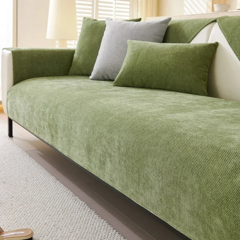 A light green sofa protection cover with gray and olive accent pillows on a white sofa.