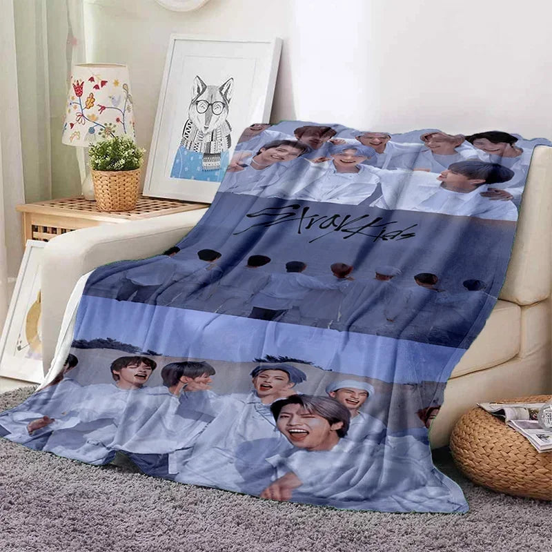 A blue and white fleece throw blanket featuring a collage of Stray Kids members' faces.