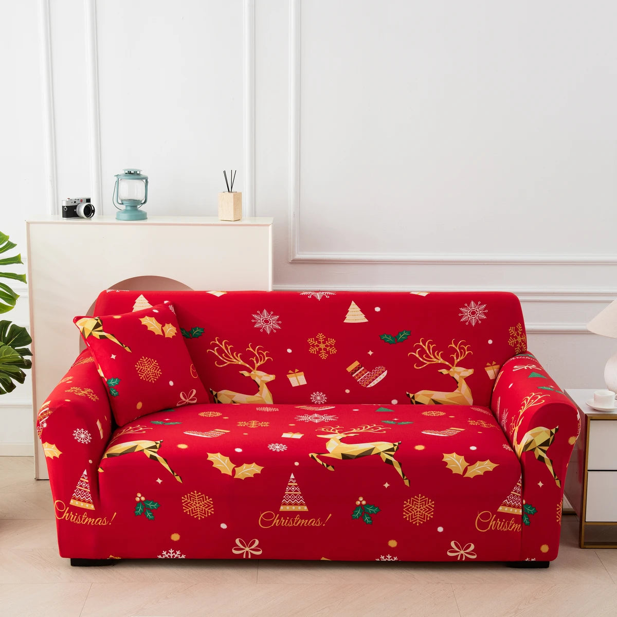 A vibrant red festive sofa cover with gold reindeer and Christmas patterns displayed indoors.